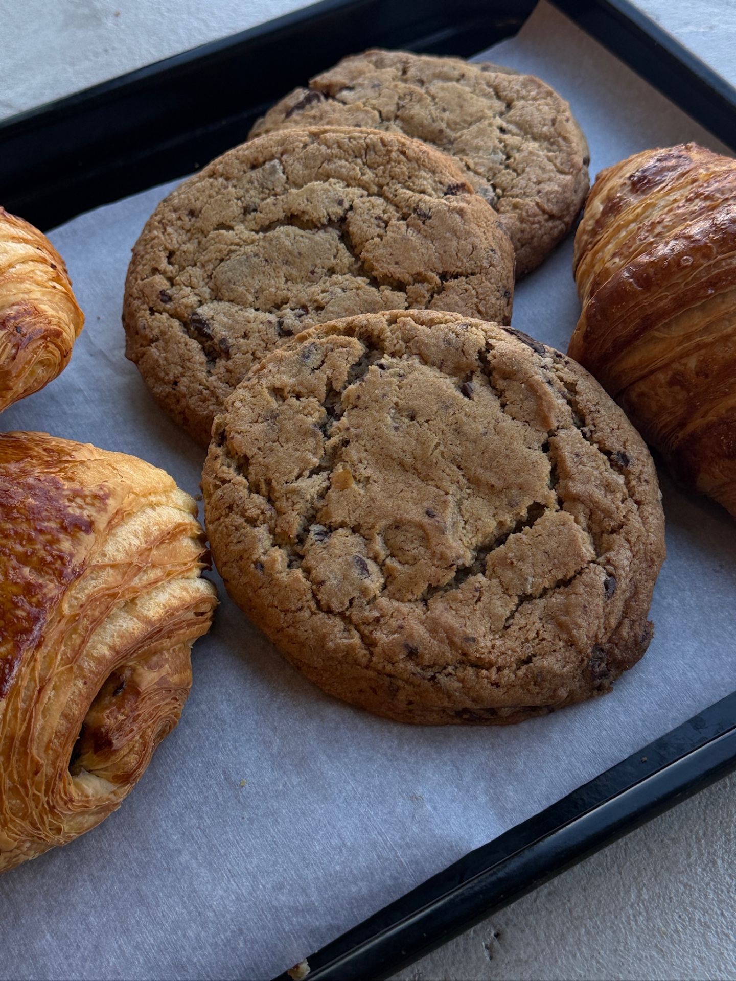 Cookies maison aux pépites de chocolat et croissants frais sur plaque
